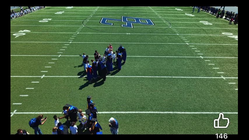 the class of 2026 and Kindergarten class of 2038 meet on football field to exchange gifts