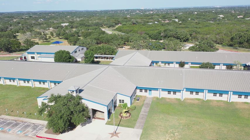 A drone flying over the school showing the front of the school flying back towards and over the playground.