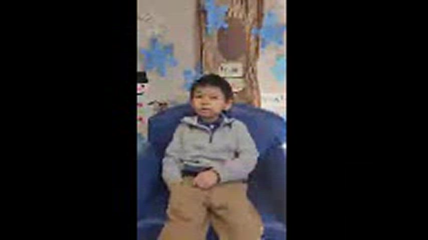 Young boy is seated in a small sized couch. 