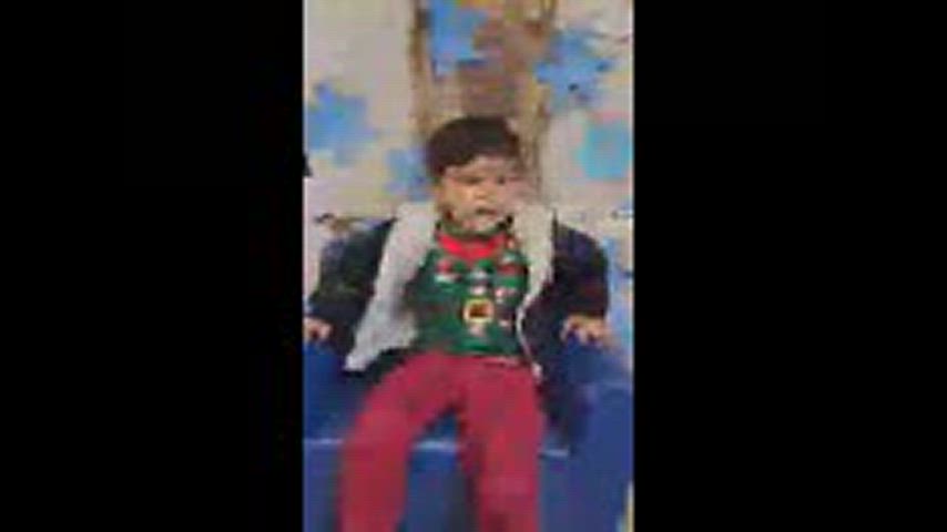 A boy is seated in a small child sized sofa.