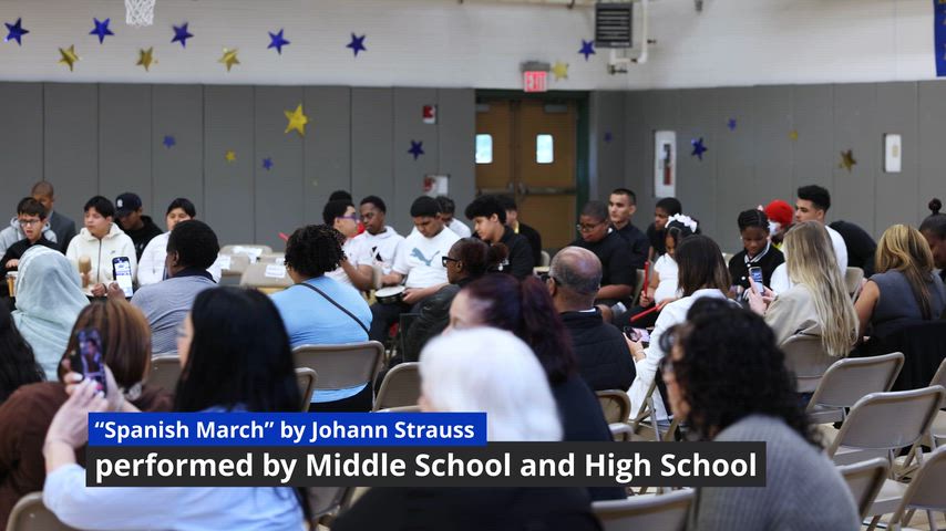 Students are singing inside of an auditorium 