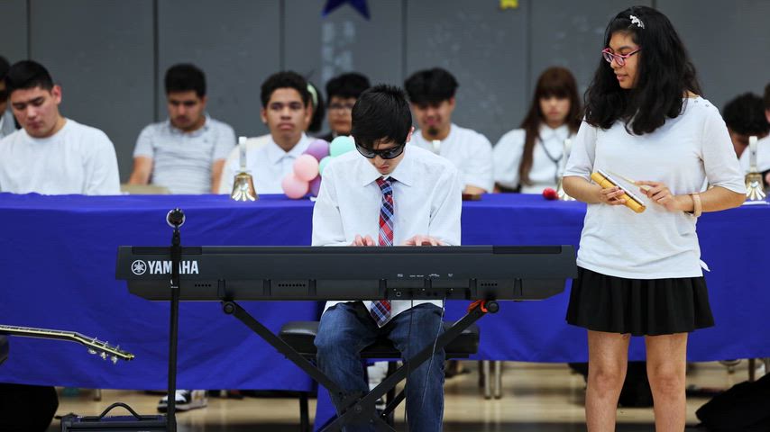 a boy plays the piano as a girl plays chimes 