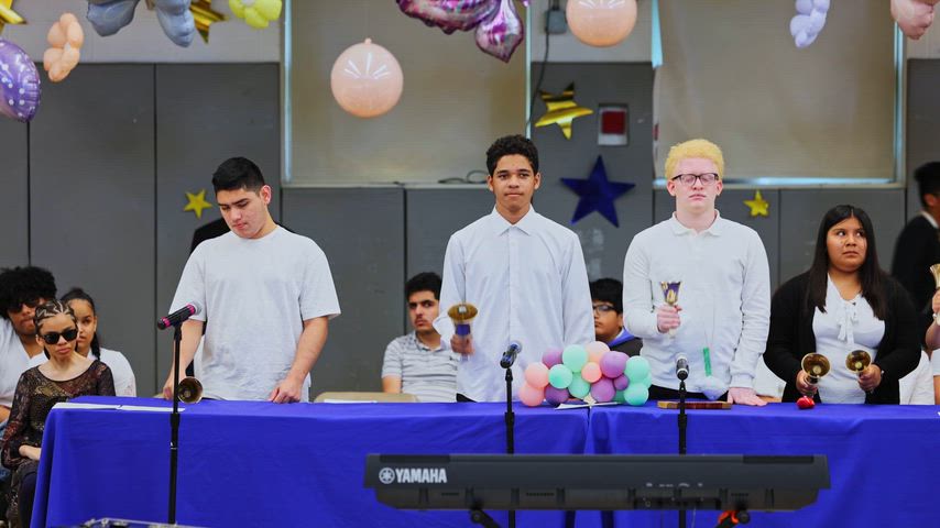 a group of students stand behind a table playing English bells 