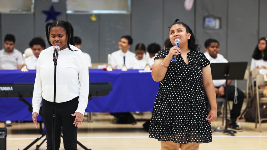 2 girls sing into a microphone w