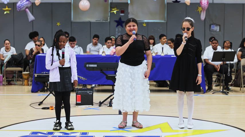 three girls sing at a microphone 