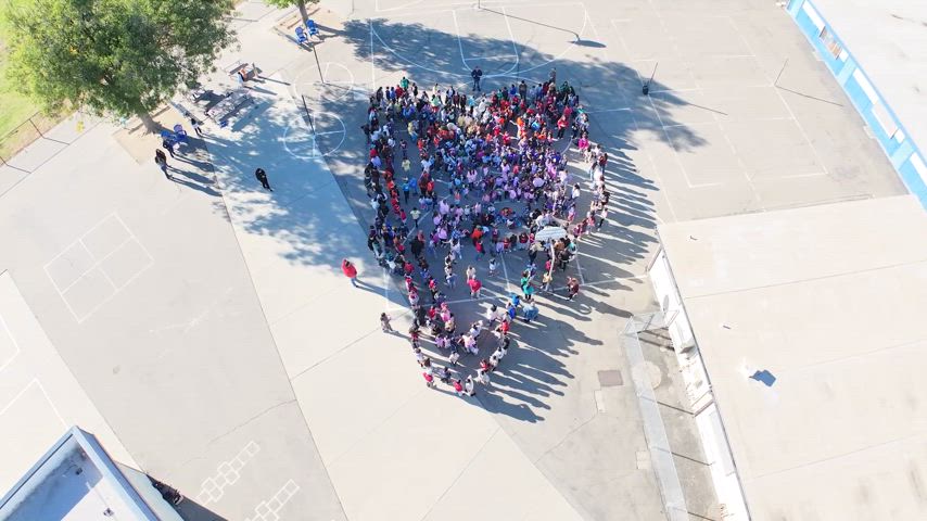 students make heart shape with their bodies as a drone gets a video from up top