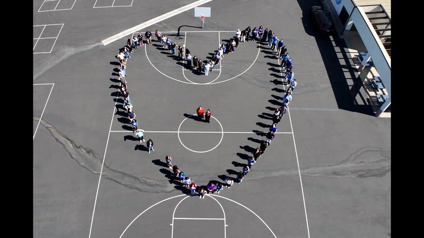 about 60 tearchers form a heart and wave in front of Park West High School