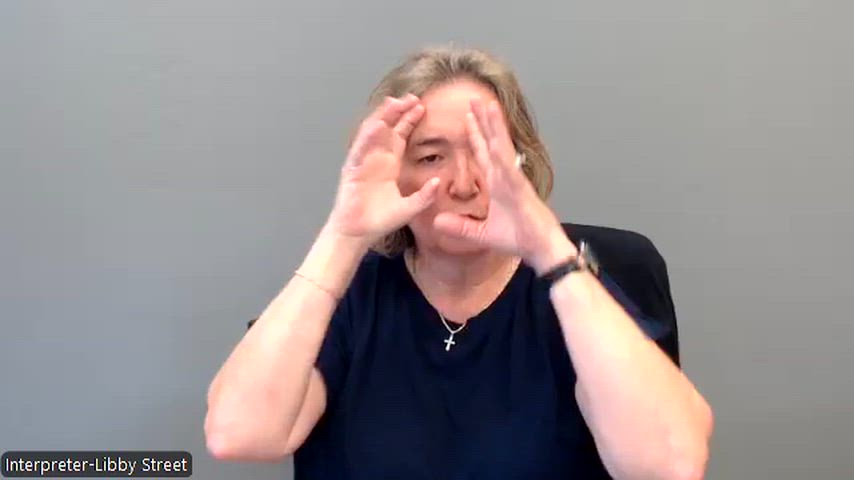 Interpreter in a black shirt on a grey background shares an update in ASL.